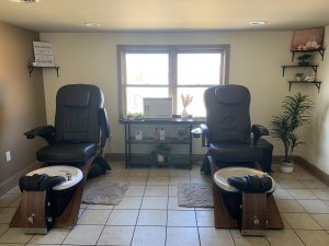 a nail spa room with 2 nail station chairs with feet soak stations